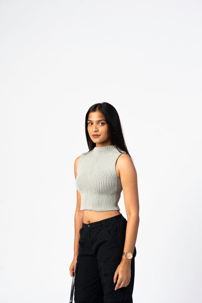 Woman wearing a sleeveless crochet top and black pants on a white background