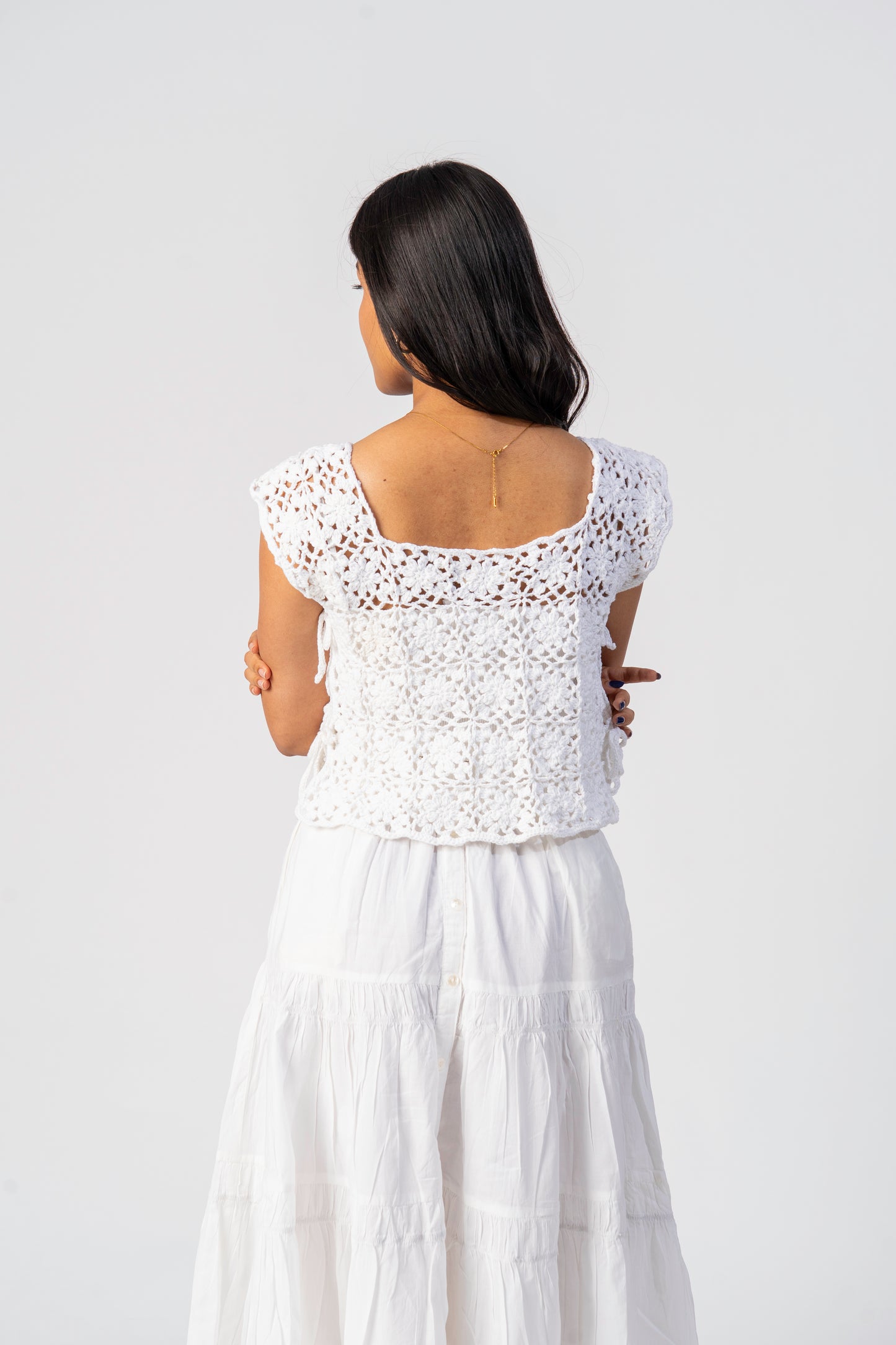 Woman wearing a white crochet top and skirt set on a plain background cover up 