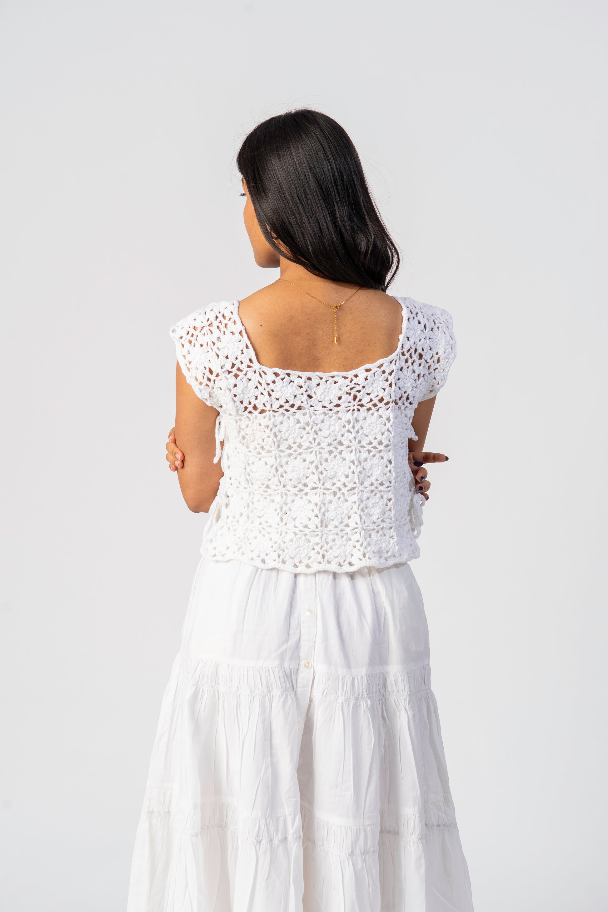Woman wearing a white crochet top and skirt set on a plain background cover up 