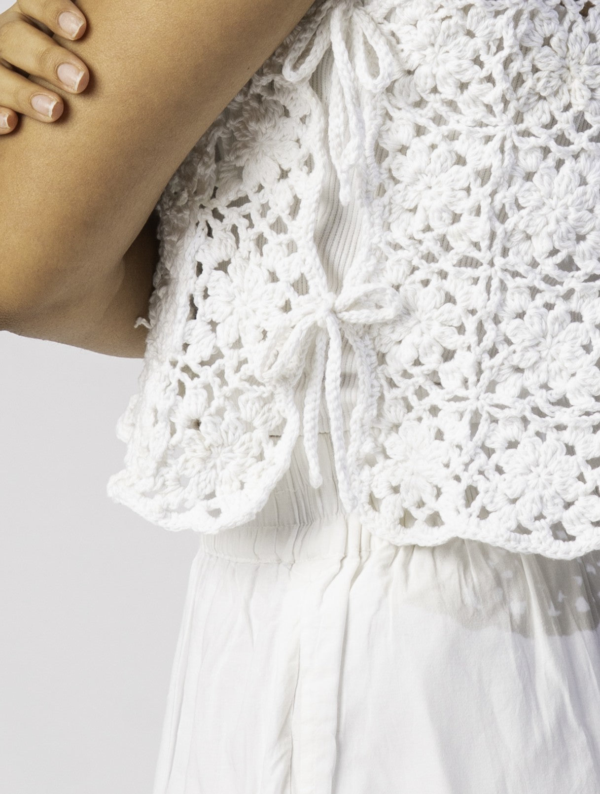 Close-up of a white crochet squares dress on a plain background