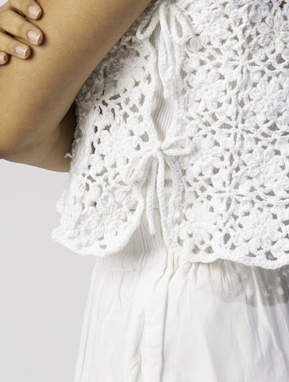Close-up of a white crochet squares dress on a plain background