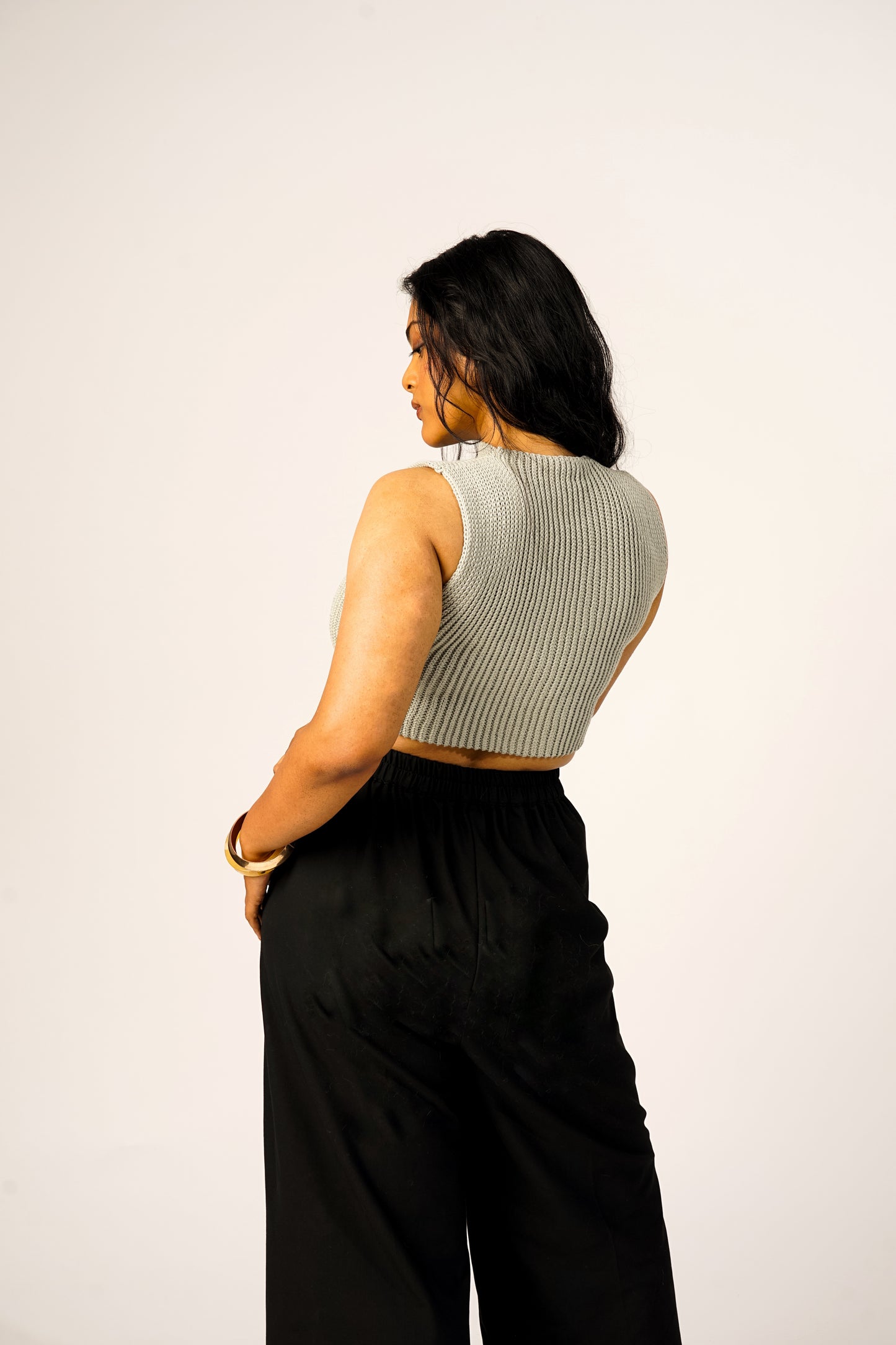 Woman wearing a sleeveless ribbed and black pants on a white background