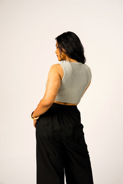 Woman wearing a sleeveless ribbed and black pants on a white background