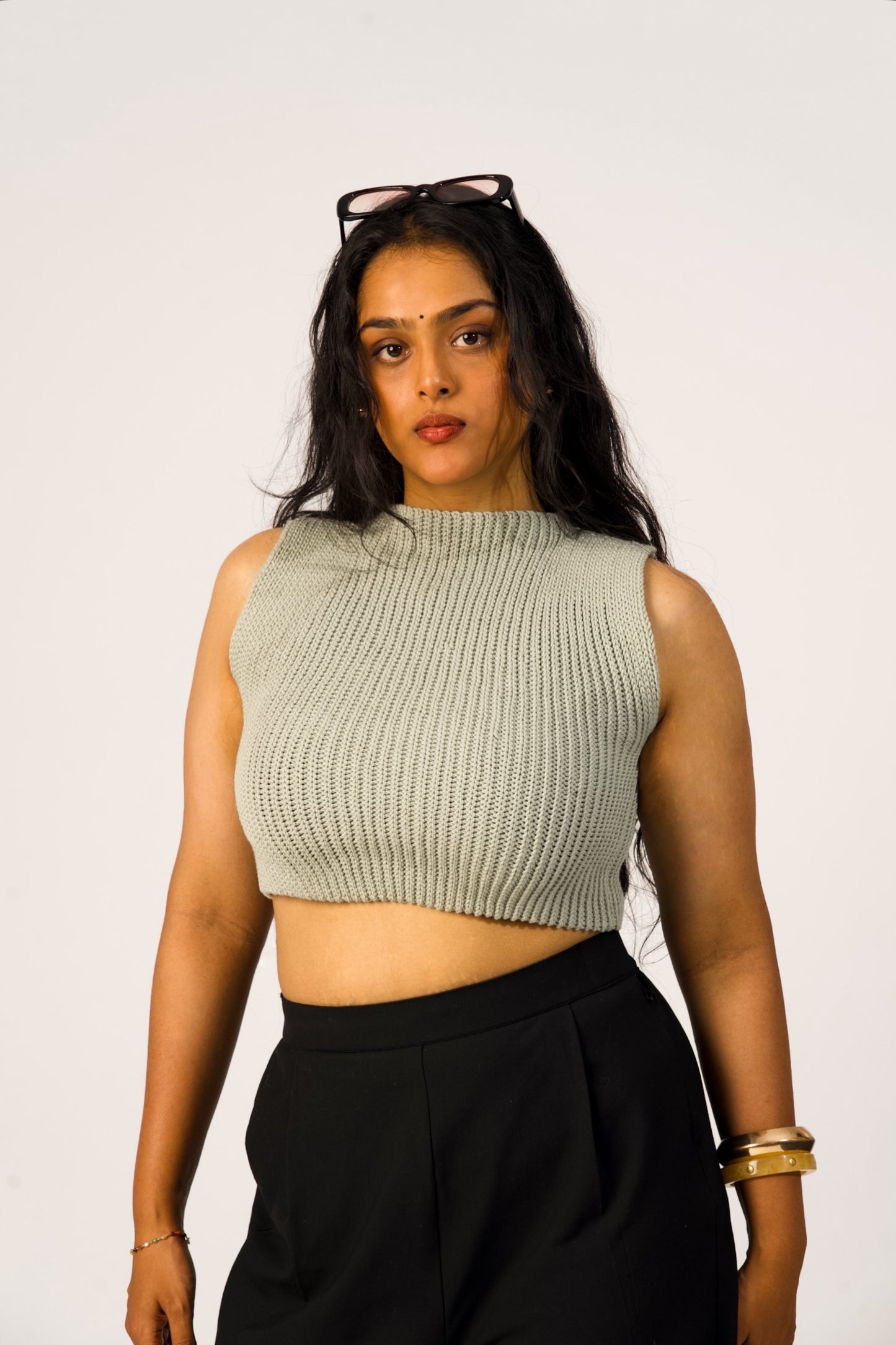 Woman wearing a sleeveless ribbed top and black pants against a white background