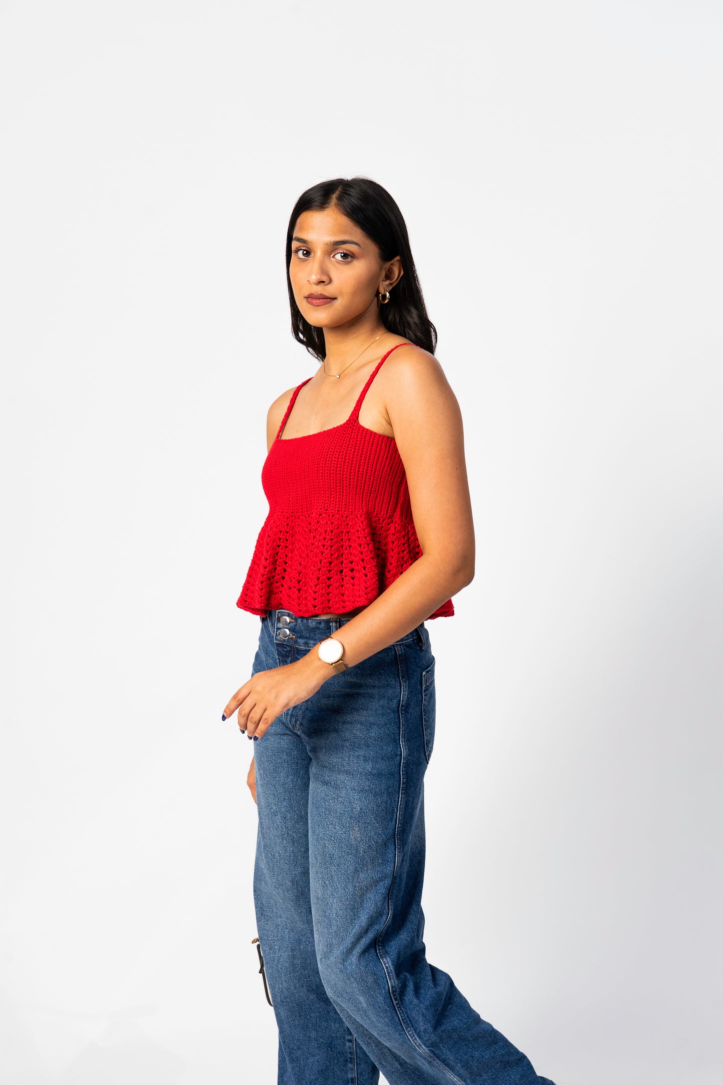 Woman wearing a red top and blue jeans on a white background